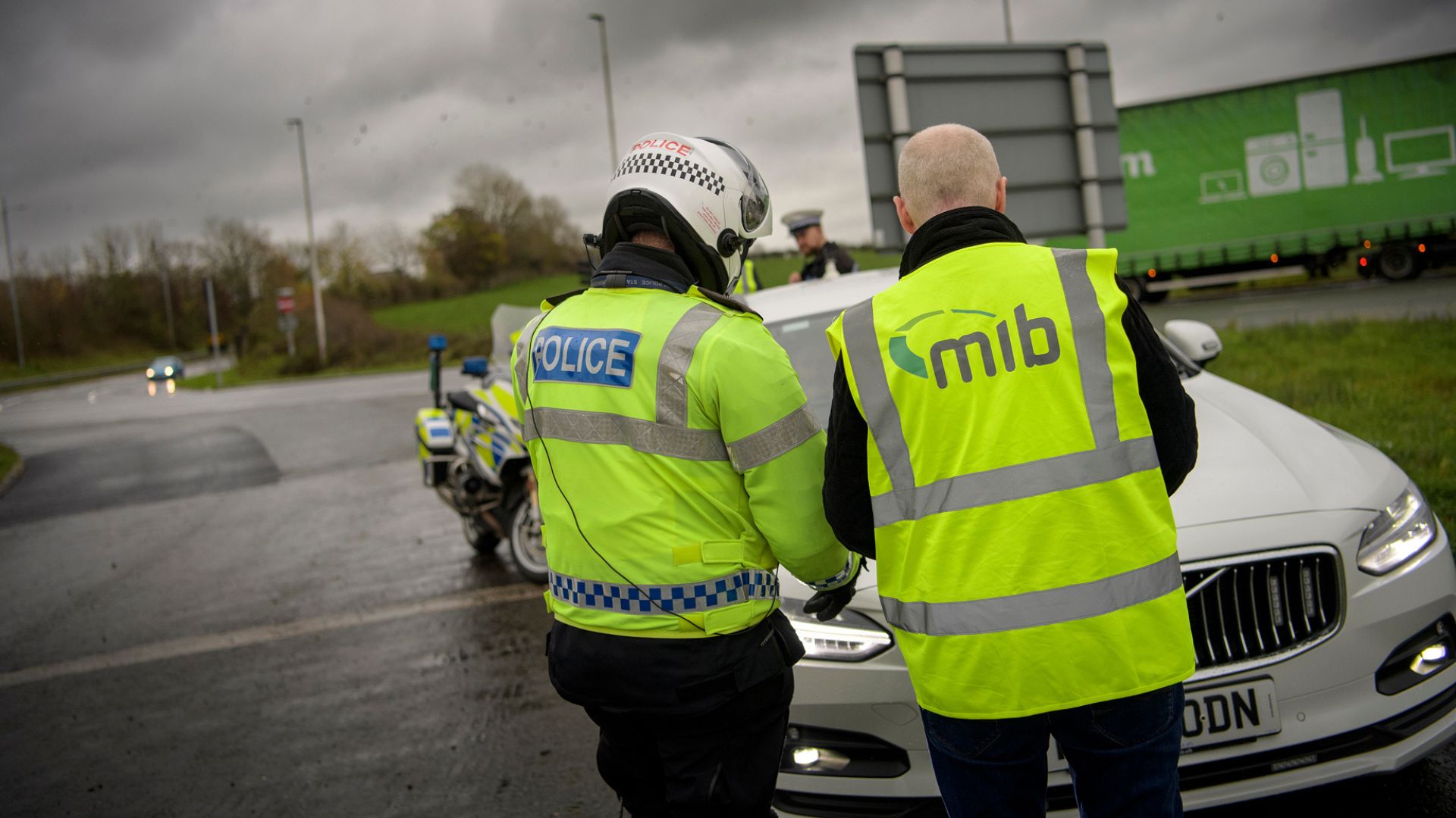 Police officer from behind looking at a car.