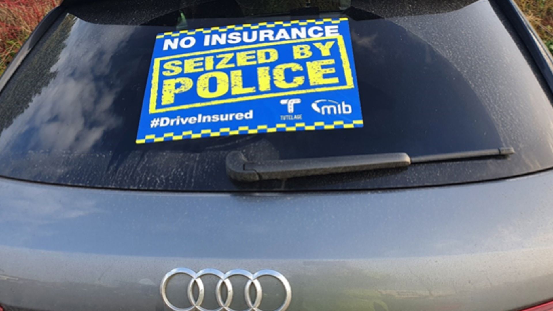 A grey Audi with an MIB 'No insurance seized by Police' sticker on the back window